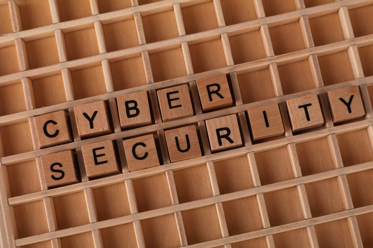 Home Wooden blocks spelling Cyber Security on a wooden grid background.